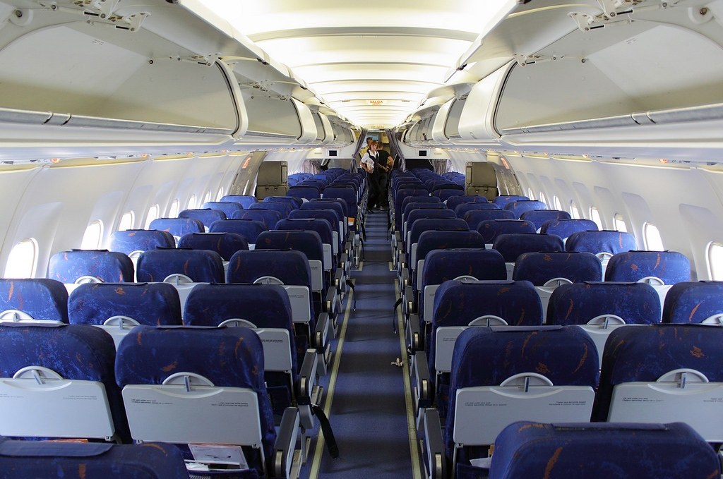 Passenger cabin with blue fabric seats and open center aisle.