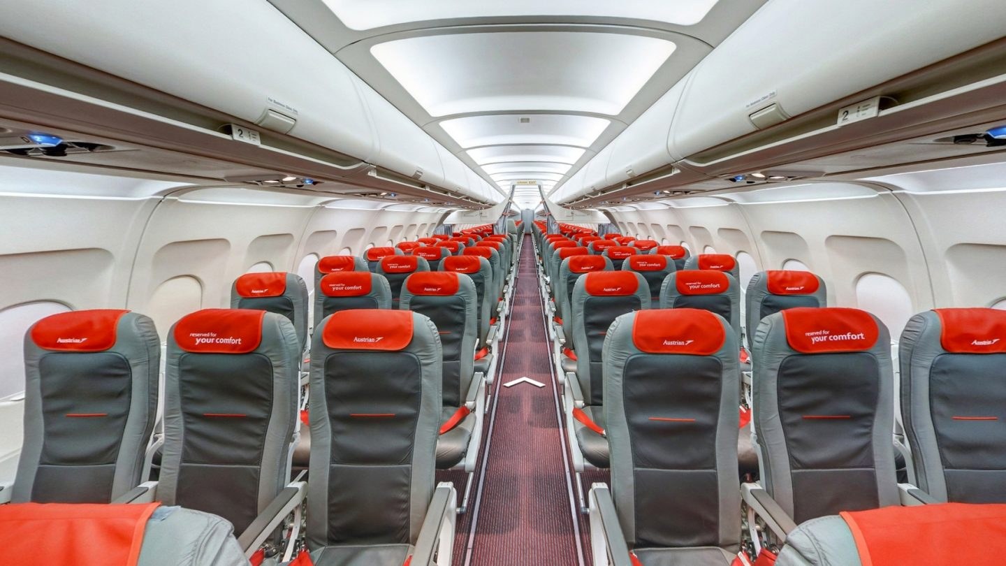 Passenger cabin with gray seats and red Austrian-branded headrests.