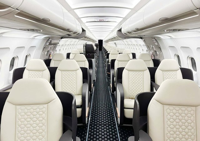 Premium aircraft cabin with cream seats and dark aisle carpet.