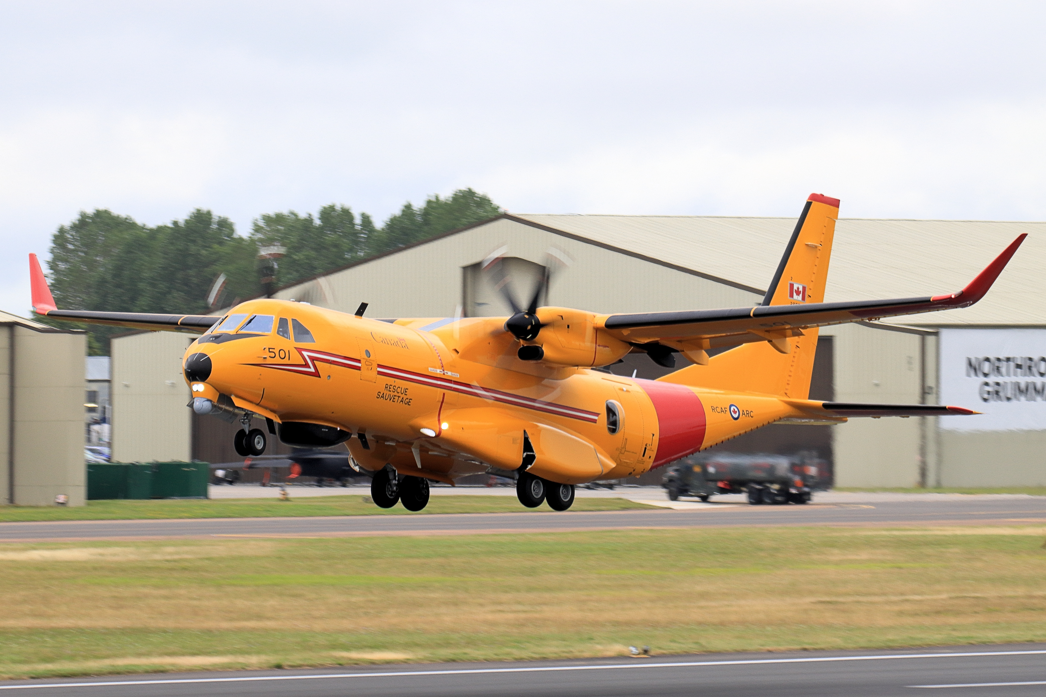Yellow RCAF CC-295W Kingfisher 501 landing with gear down near hangars.