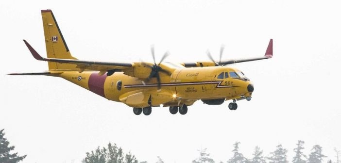 Yellow RCAF CC-295W Kingfisher 501 airborne over trees with landing gear down.
