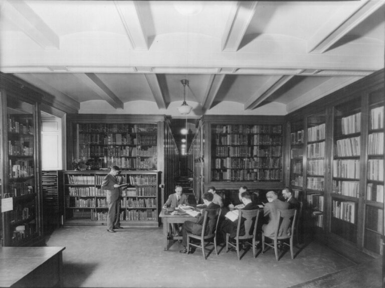 Men reading at a table in a book-lined room at the Library of Congress