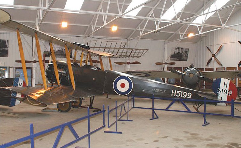 Avro 504 H5199 flying in rear-quarter view with tail and wing markings visible.