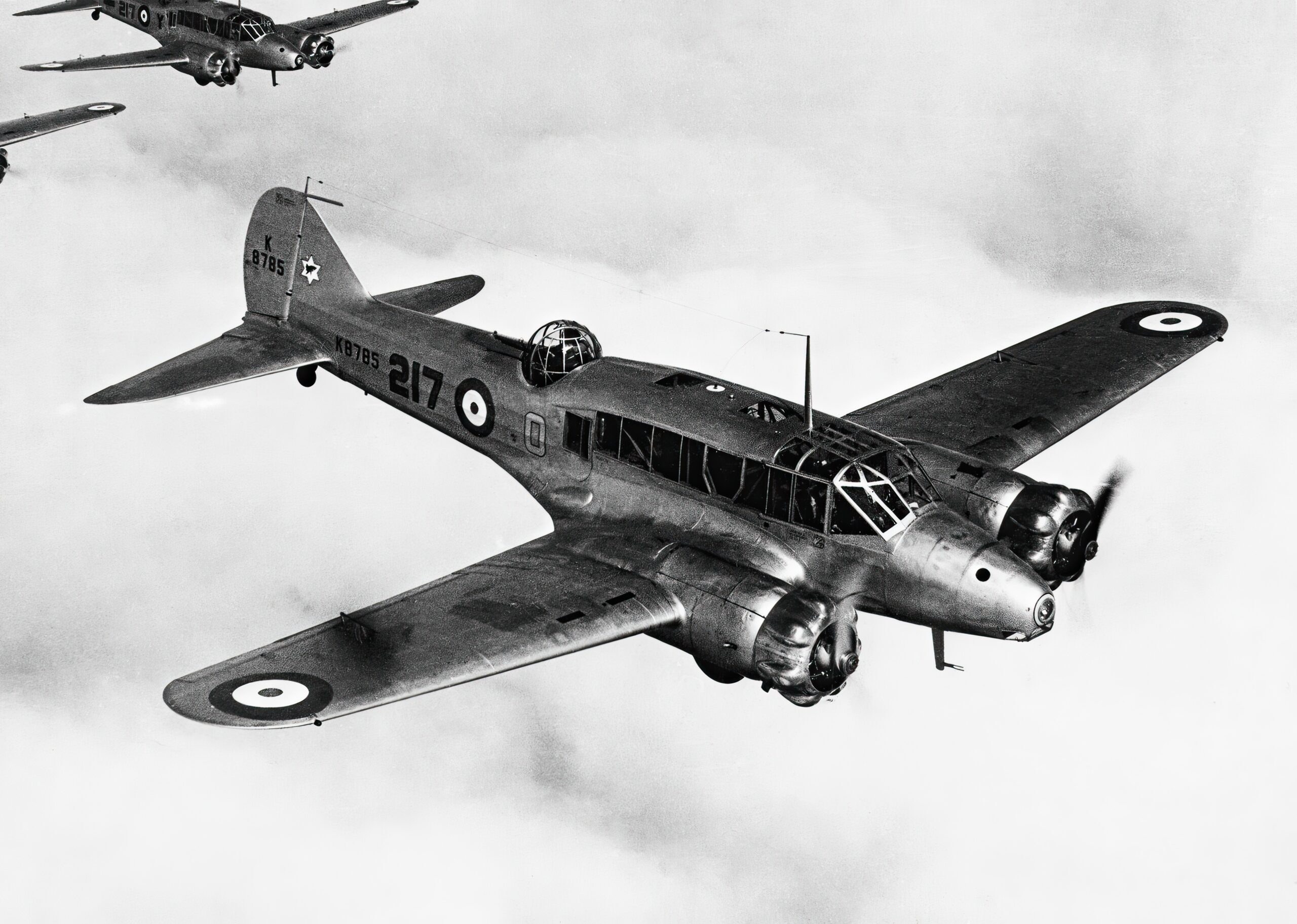 Black-and-white Avro Anson K8785 flying in formation with other Ansons.