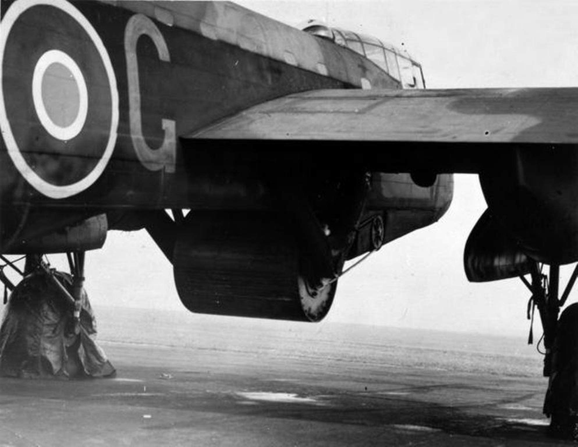 Black-and-white close view of a Lancaster fuselage, wing root, bomb bay area, and landing gear.
