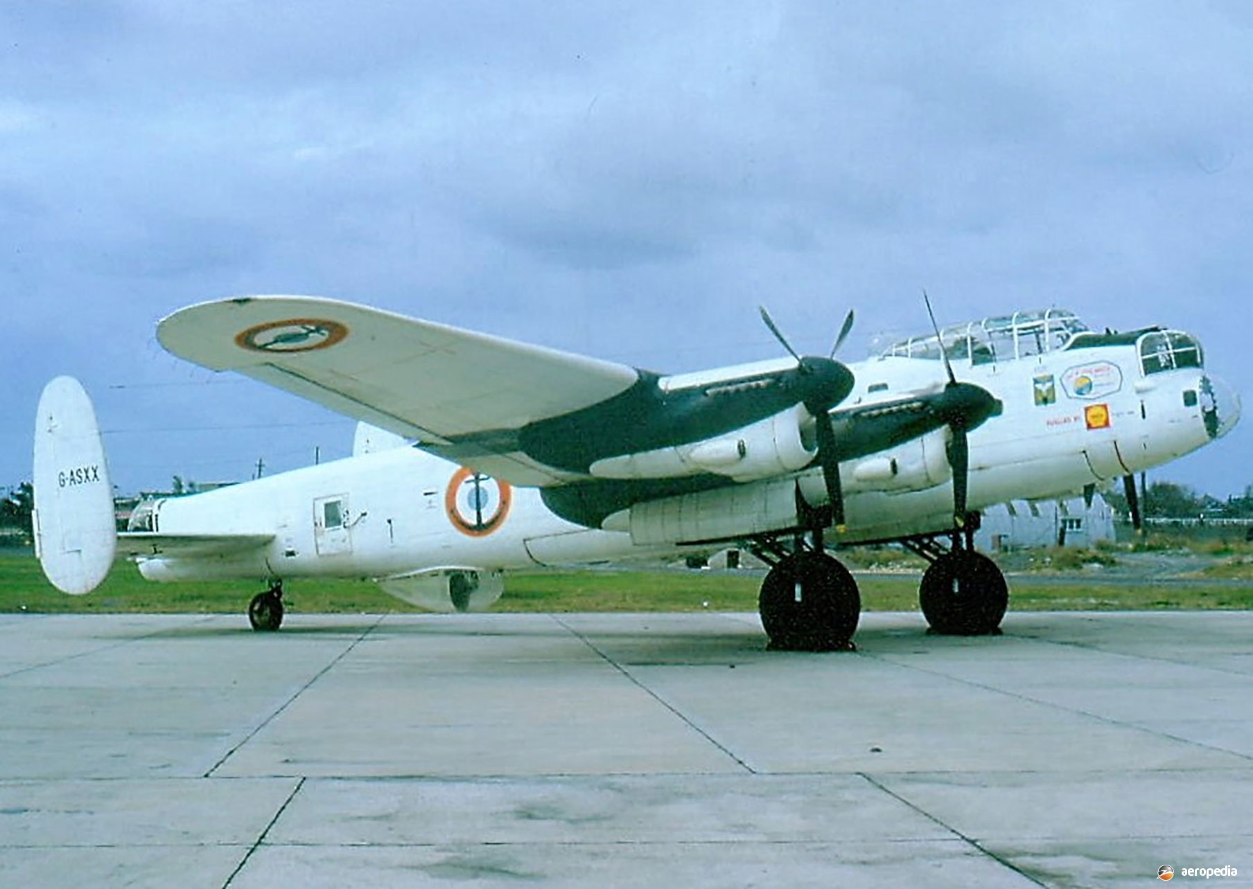 White four-engine Lancaster marked G-ASXX parked on a concrete ramp.
