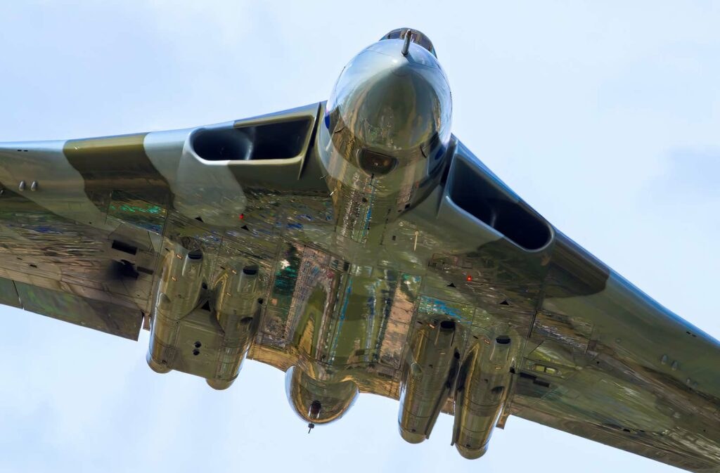 Underside view of an Avro Vulcan banking against a blue sky.