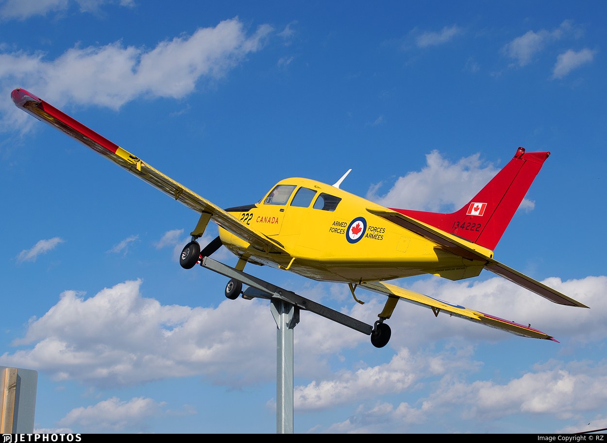 Yellow and red Beechcraft CT-134 Musketeer 134222 displayed on a pedestal.