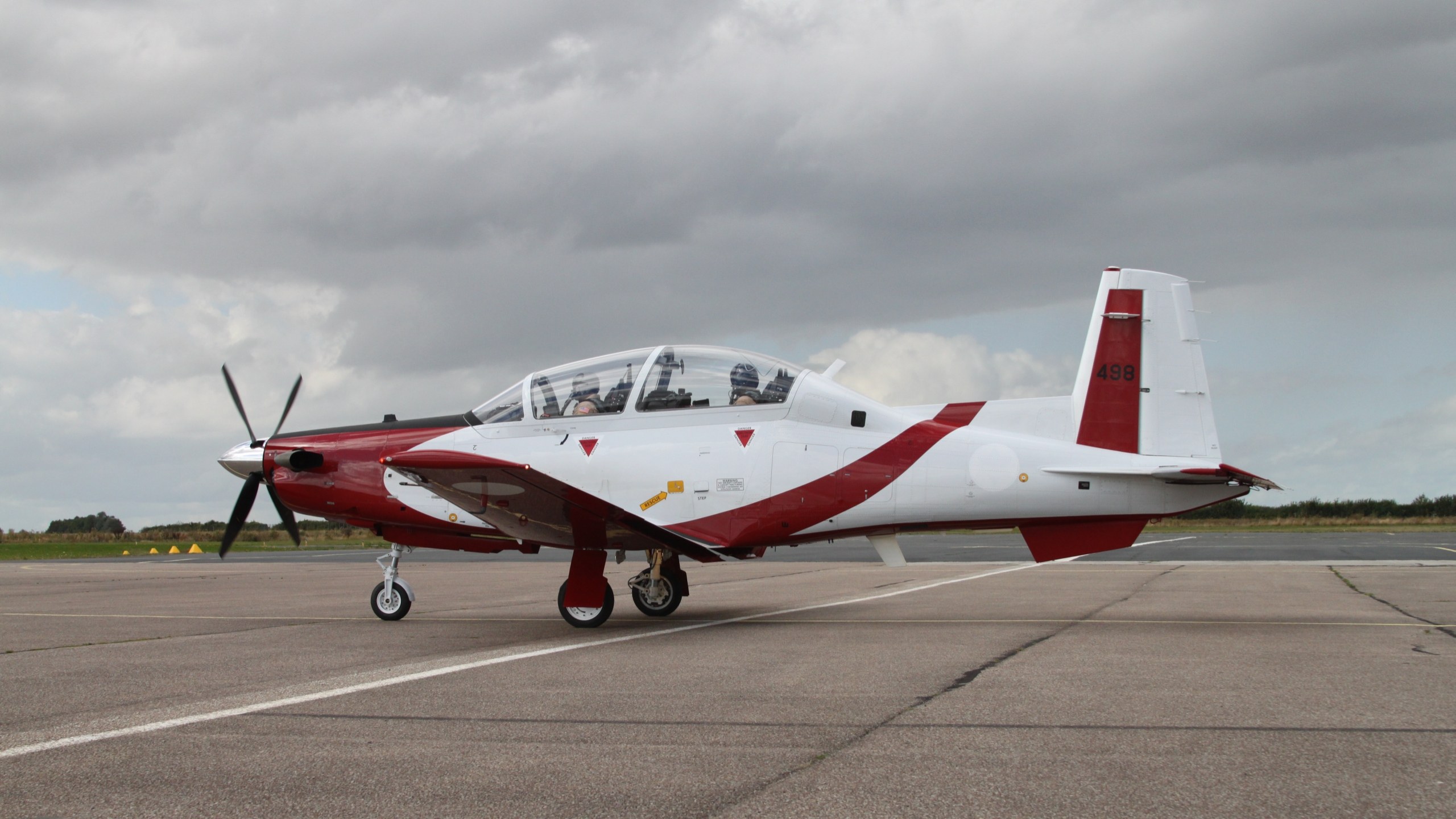 Red and white Beechcraft Texan trainer 498 parked on a runway apron.