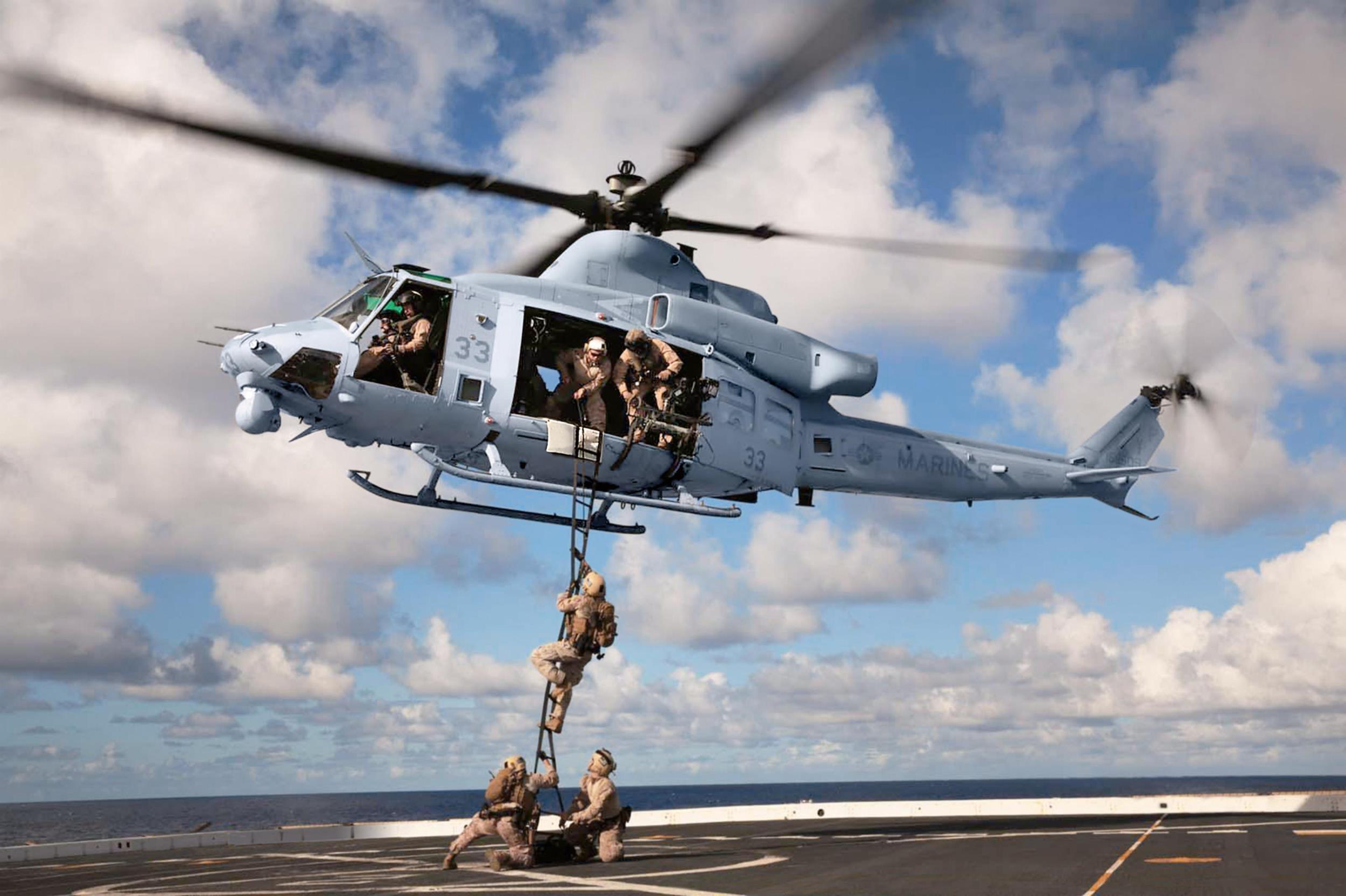 Marine Bell UH-1Y hovering over a ship deck during a rope exercise.