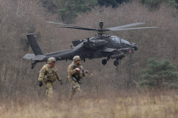 Boeing AH-64 Apache - Troops and a Boeing AH-64 Apache attack helicopter of the U.S. Army 12th Combat Aviation Brigade participate in the Allied Spirit 25 mili...