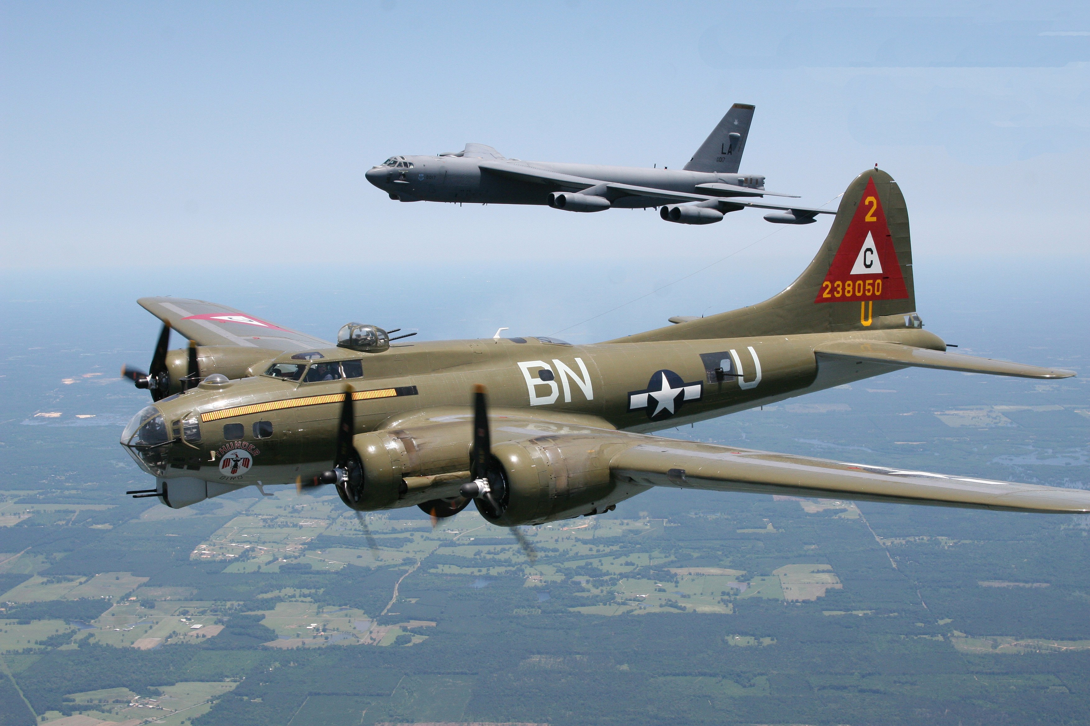 Olive drab Boeing B-17 BN-U flying below a gray B-52 bomber.