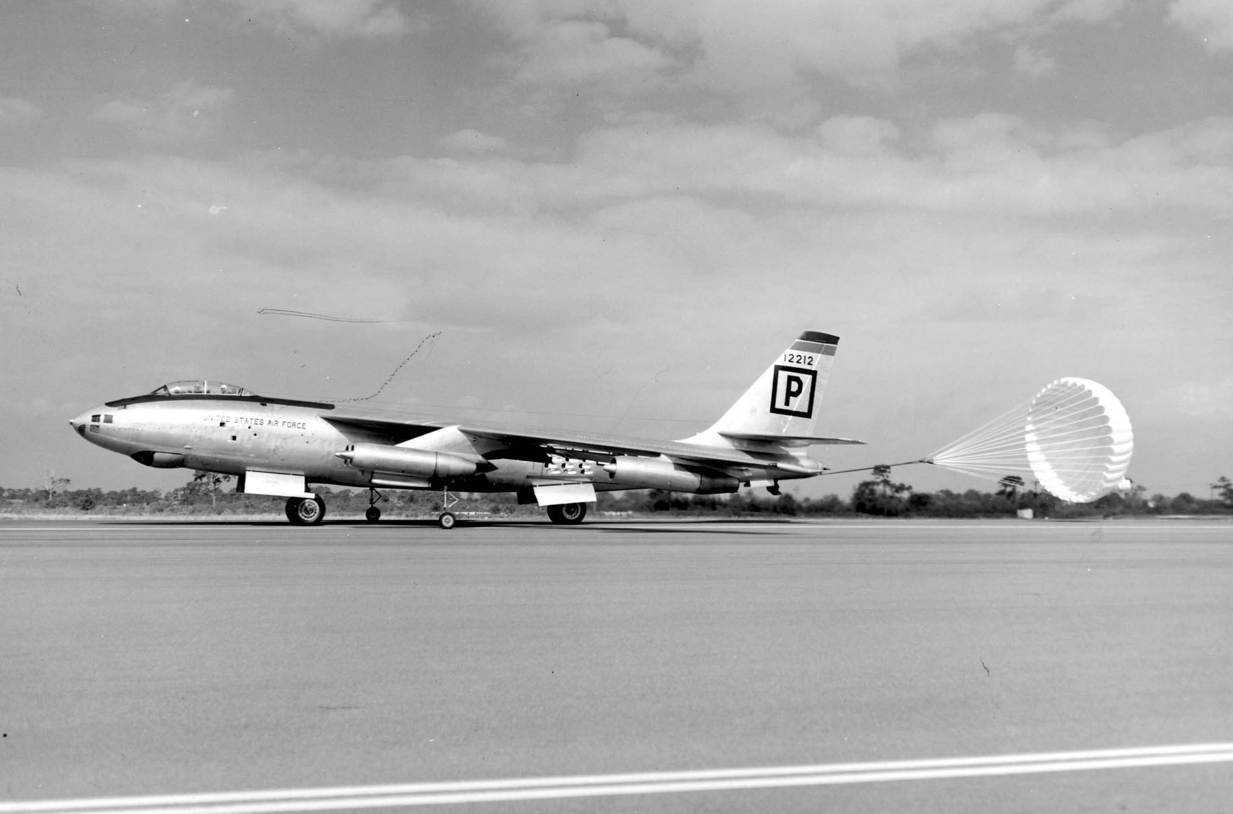 Black-and-white photo of Boeing B-47 12212 rolling on runway with braking parachute deployed.