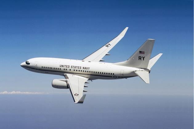 White U.S. Navy Boeing C-40A marked RY flying above the ocean.