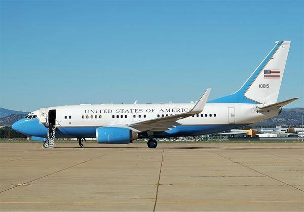 Blue-and-white Boeing C-40 00015 parked on a ramp with stairs at the forward door.