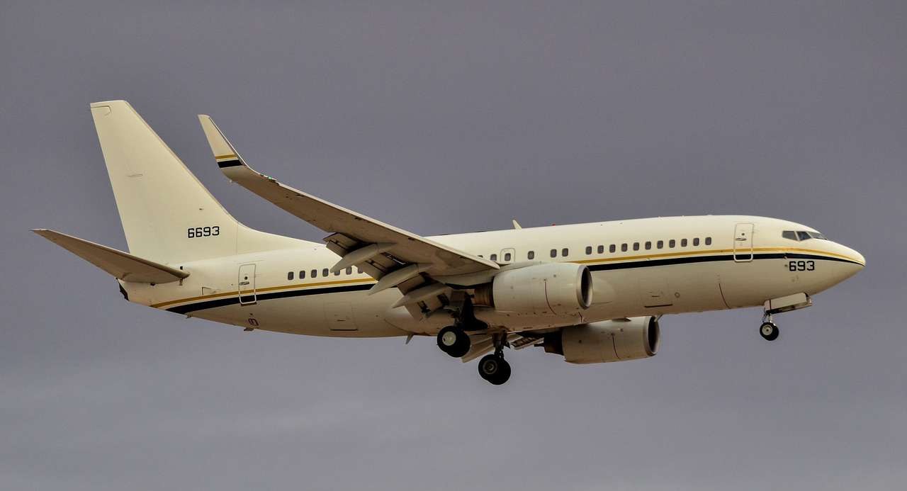 Cream-colored Boeing C-40 693 flying with landing gear extended.