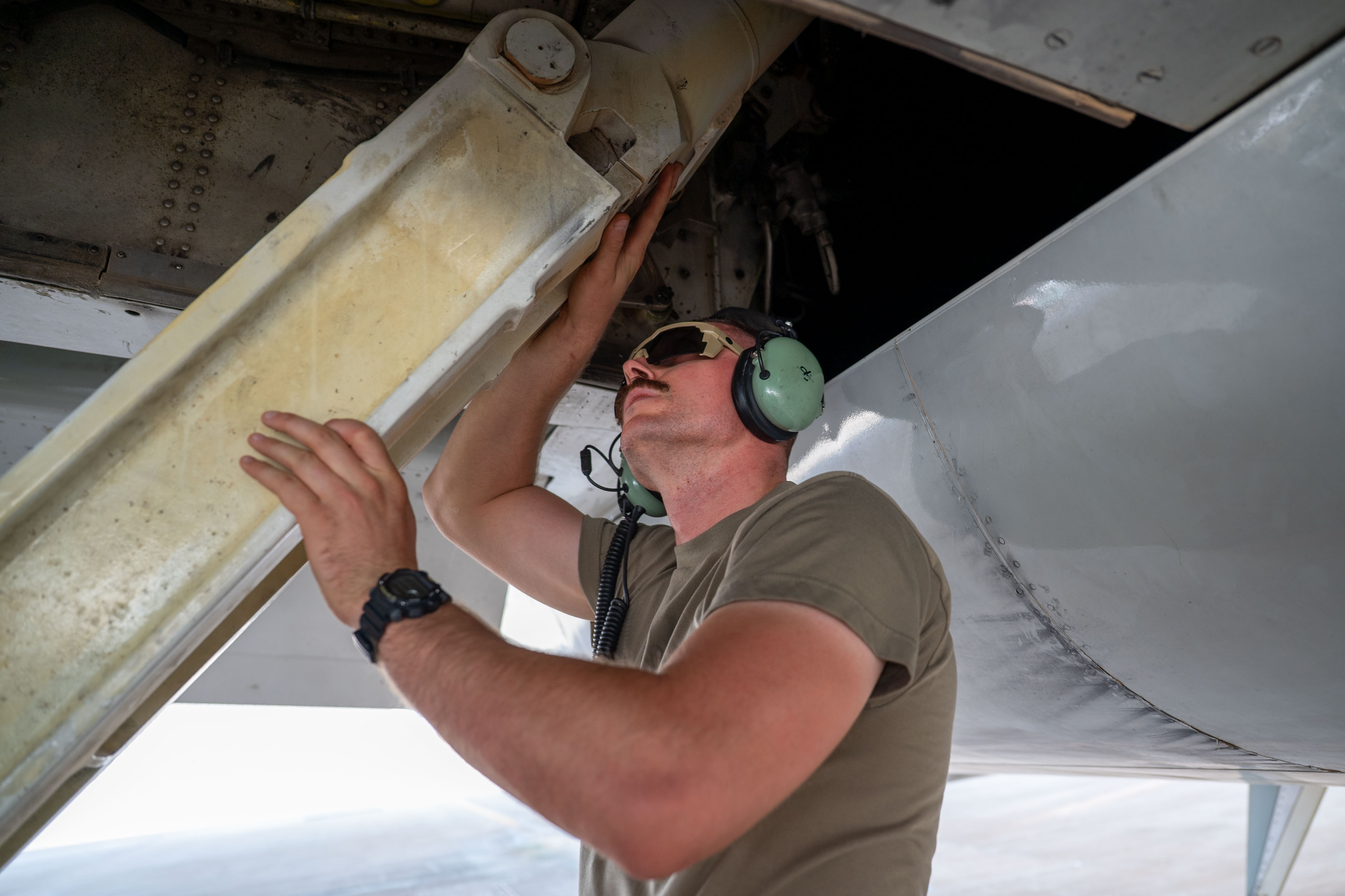 Maintainer wearing headset working beneath an E-3 Sentry aircraft panel.