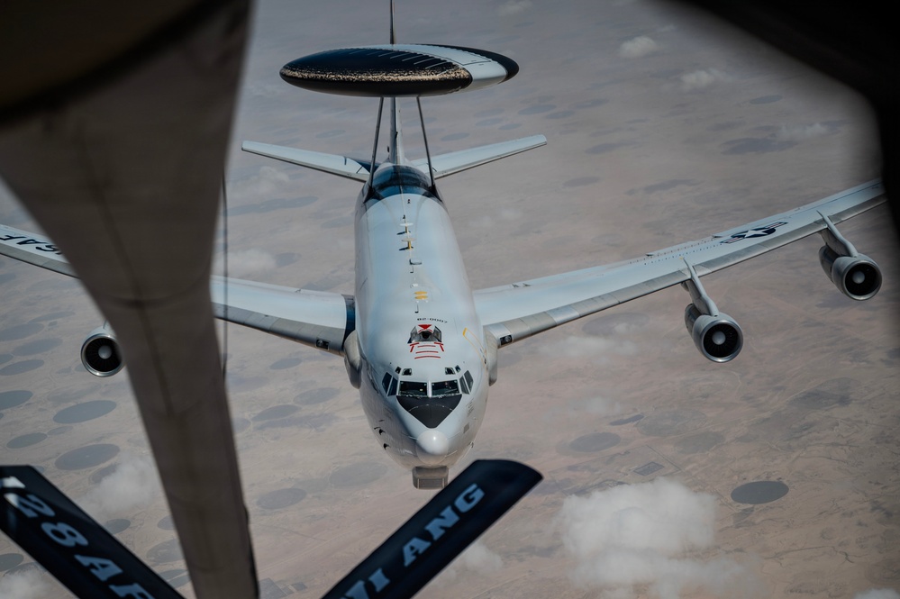 Boeing E-3 Sentry nose and radar dome seen below a tanker boom.