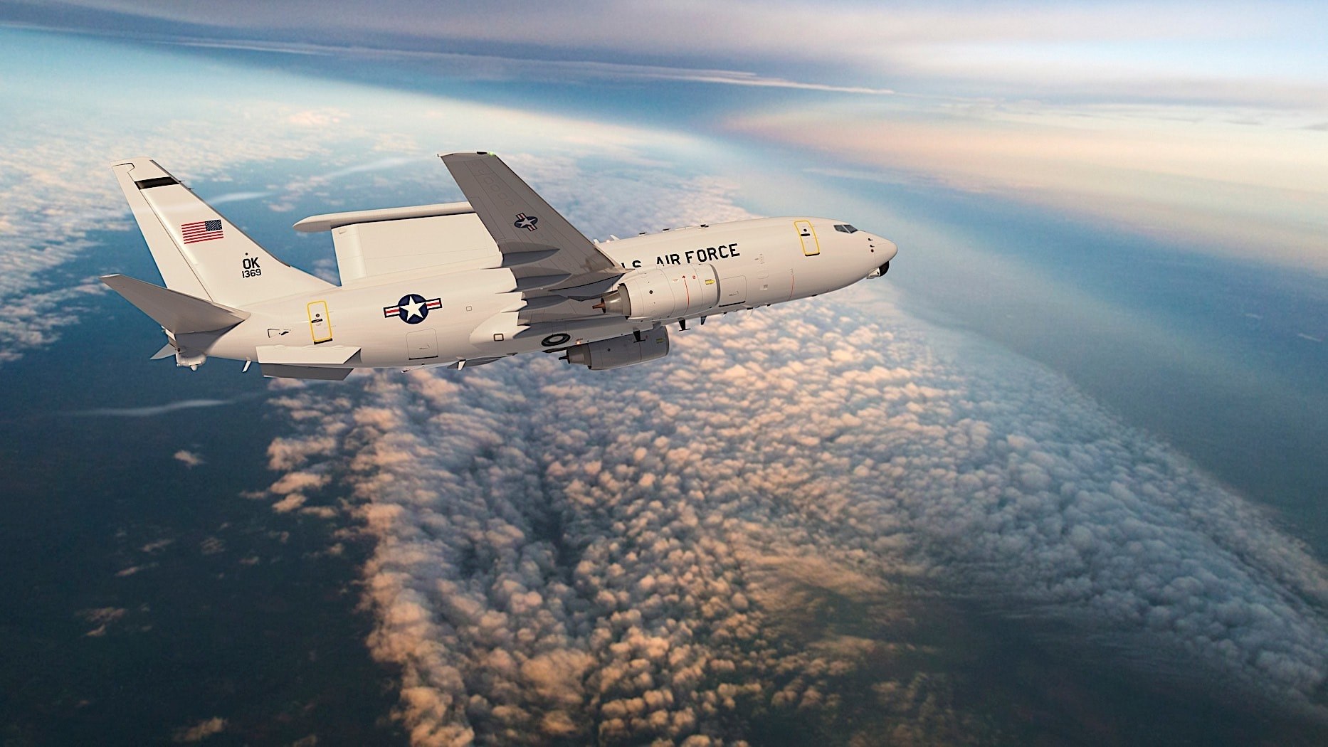 U.S. Air Force Boeing E-7 Wedgetail flying above clouds with OK 1369 tail markings.