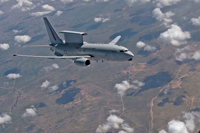 Royal Australian Air Force Boeing E-7 Wedgetail flying over land and scattered clouds.