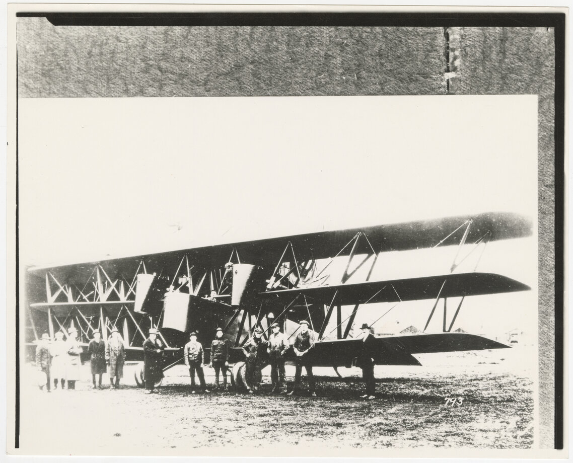 People standing in front of a Boeing GA-1 triplane parked outdoors.