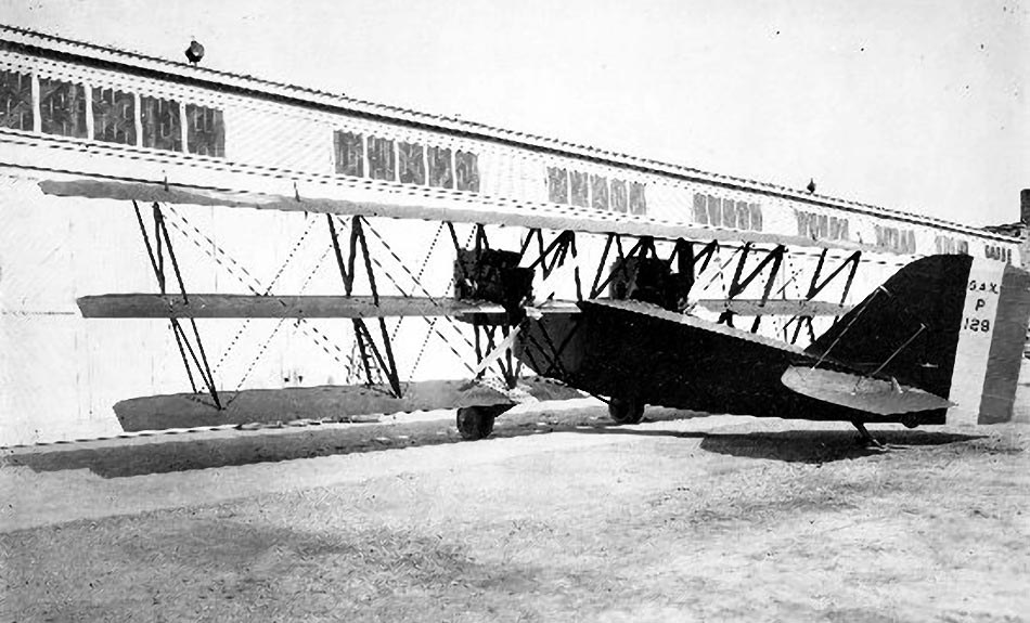 Boeing GA-X triplane parked beside a hangar in snow or bright ground.