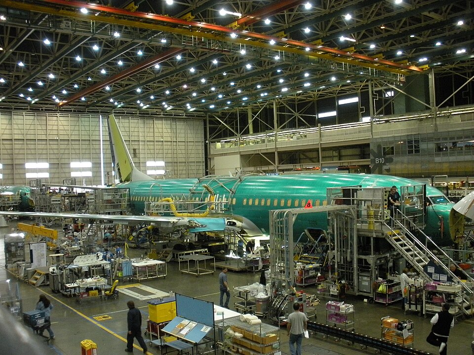 Interior view of the Boeing Renton Plant with aircraft fuselages and assembly work visible on the production floor.