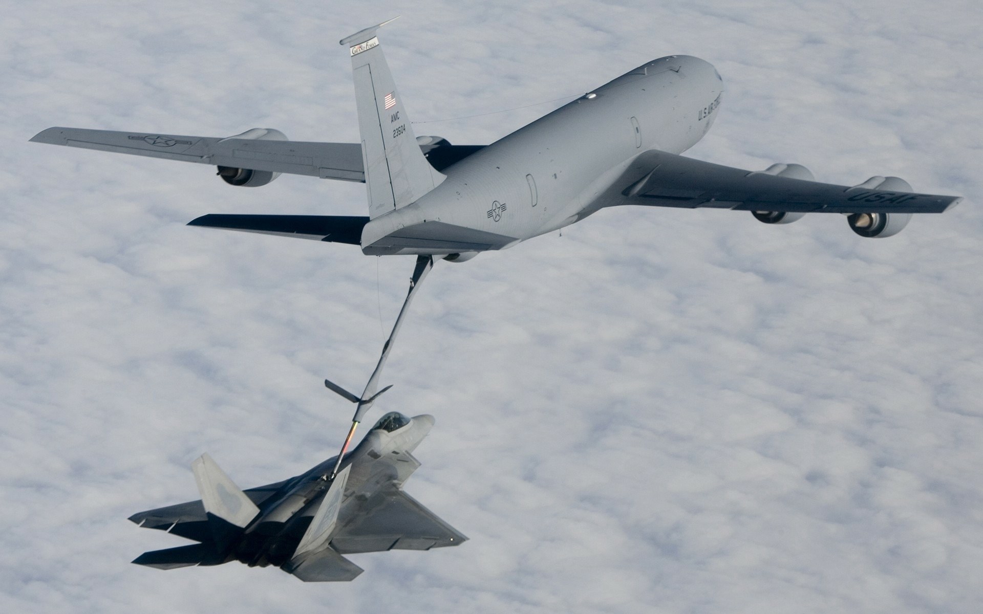 KC-135 Stratotanker refueling an F-22 above clouds.