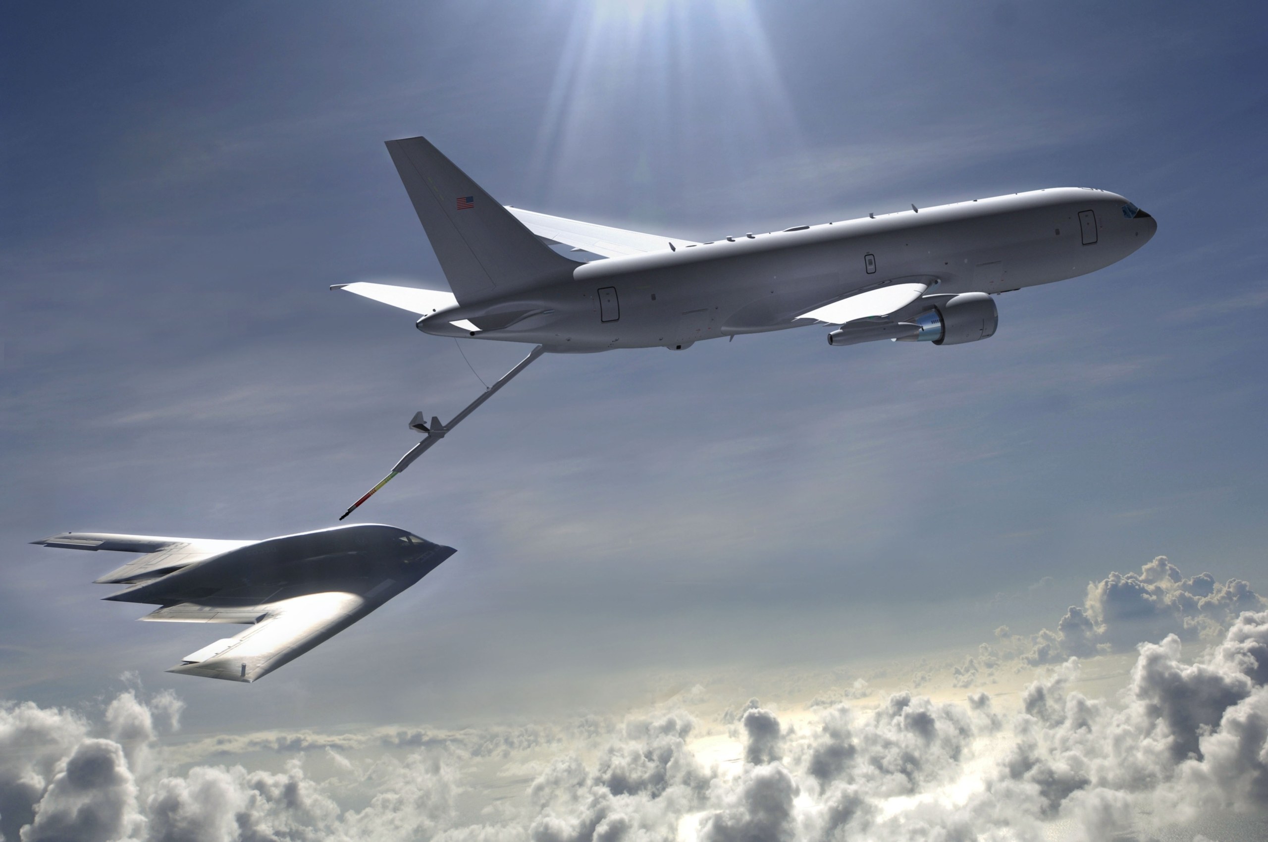 KC-46 Pegasus extending a refueling boom toward a flying-wing aircraft above clouds.