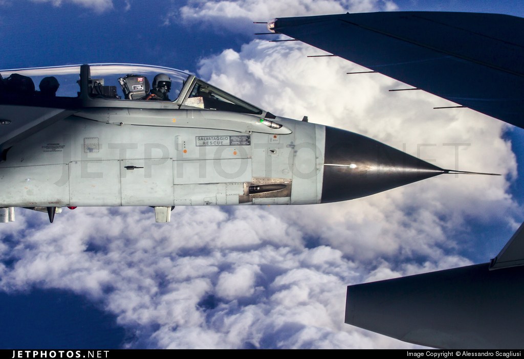 Fighter cockpit and nose below the wing of a tanker aircraft.