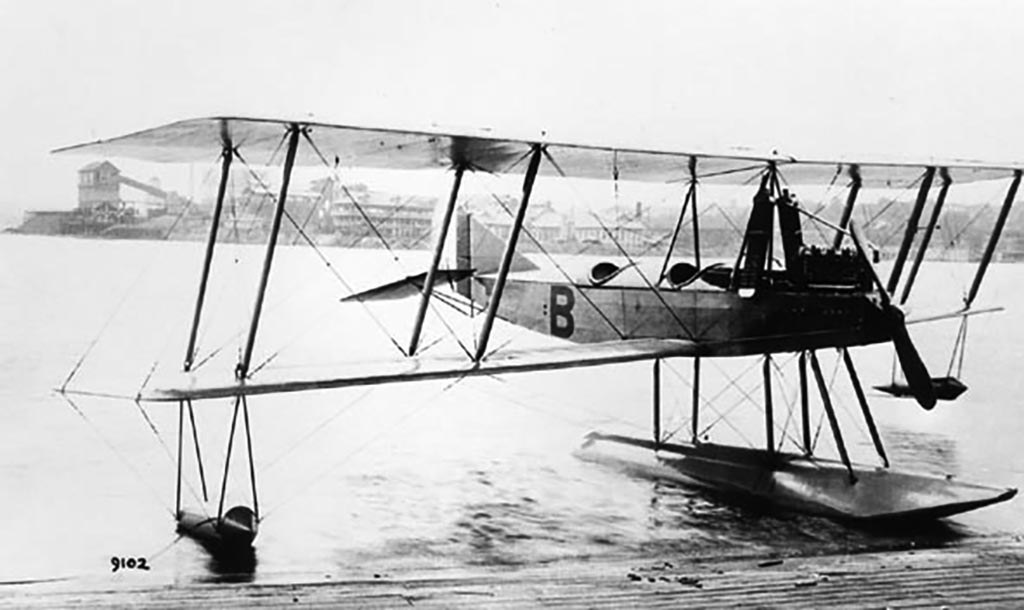 Boeing Model C floatplane marked B floating beside a dock.
