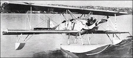 Boeing NB biplane on floats in a side view over water.