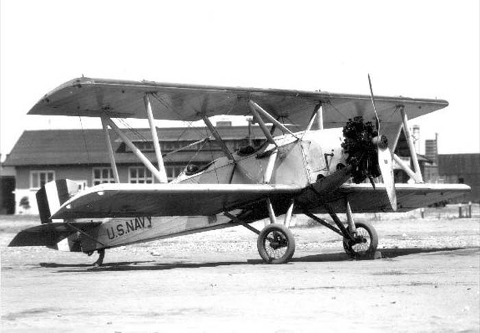 U.S. Navy Boeing NB biplane parked on wheels near buildings.