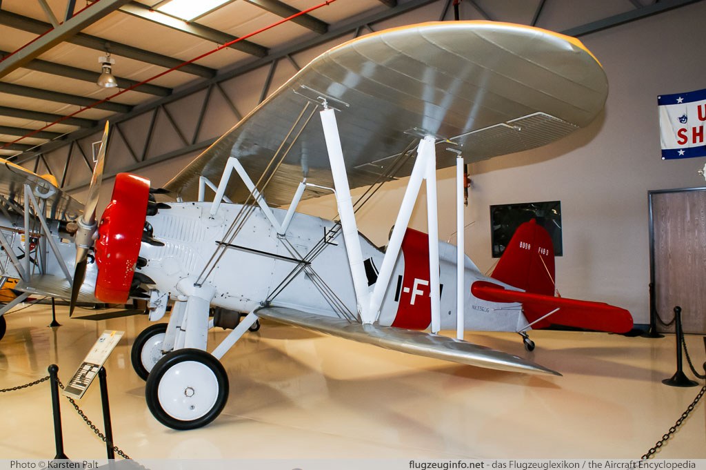 Boeing P-12-type biplane displayed indoors with red tail and cowling.