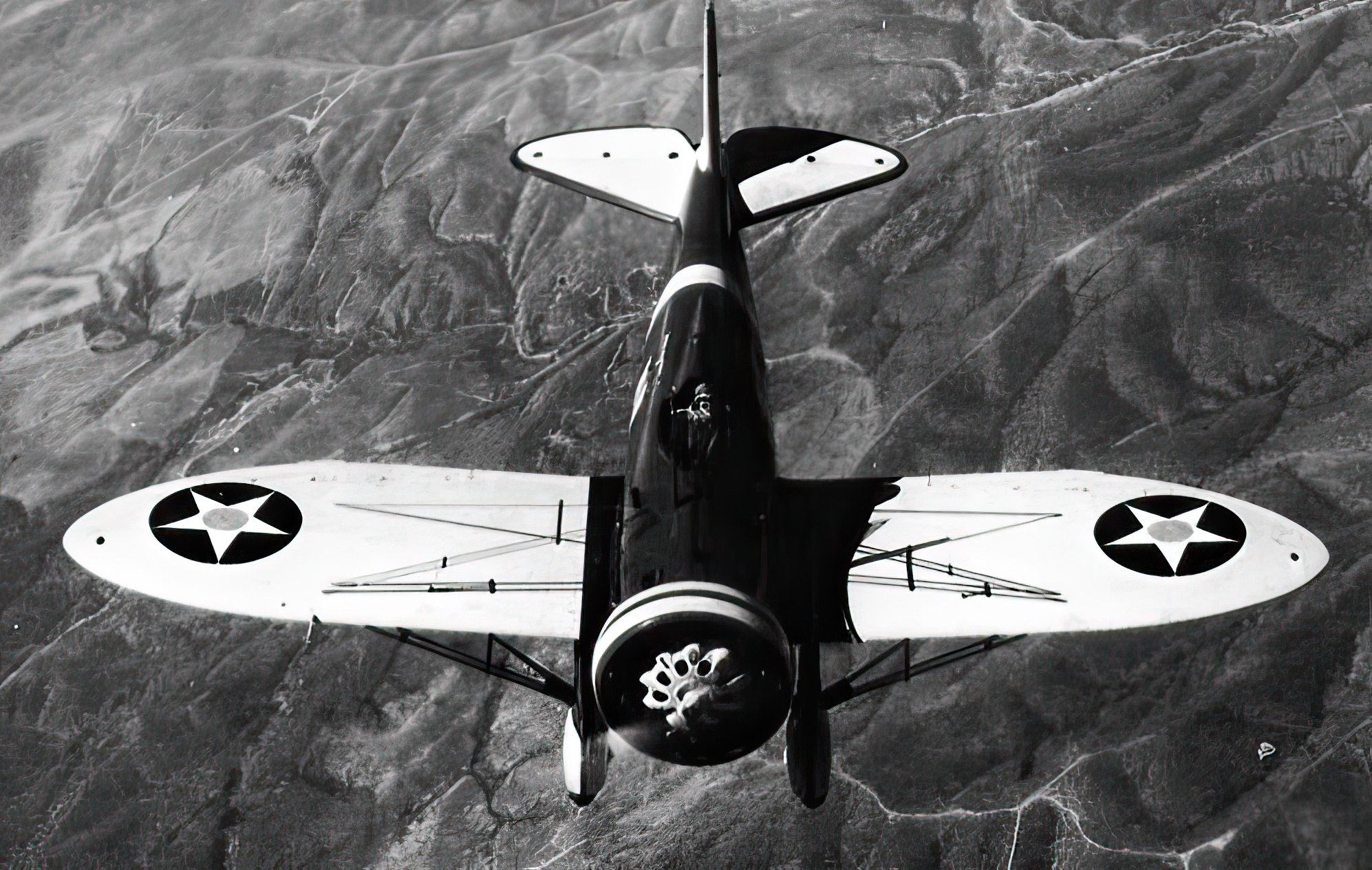 Black-and-white overhead view of a Boeing P-26 Peashooter in flight.