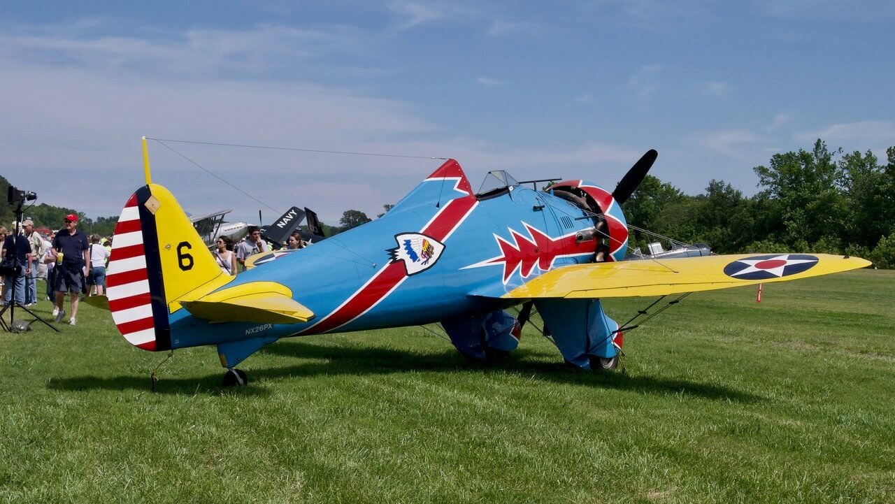 Blue Boeing P-26 Peashooter number 6 viewed from the left rear on grass.