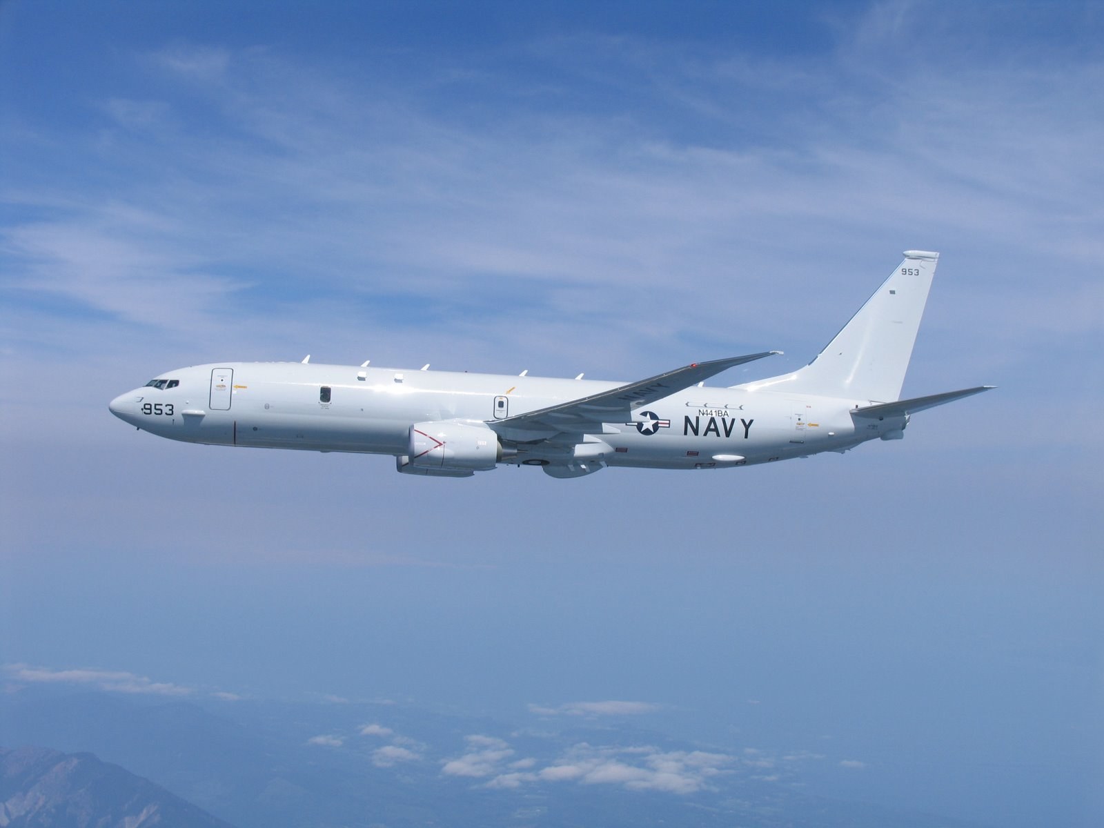 U.S. Navy P-8 Poseidon 953 flying in side profile against a blue sky.