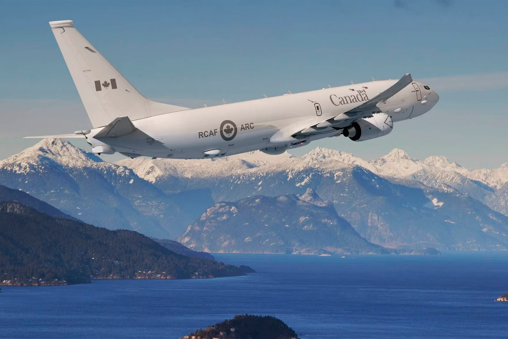 Canadian-marked P-8-style twin jet climbing above mountains and water.