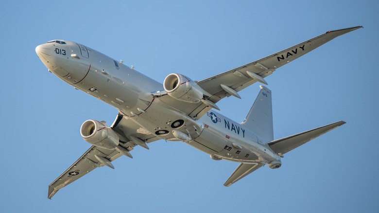 U.S. Navy P-8 Poseidon 013 passing overhead against a blue sky.
