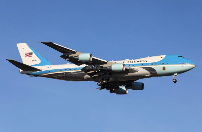 Boeing VC-25 28000 flying with landing gear extended against a blue sky.