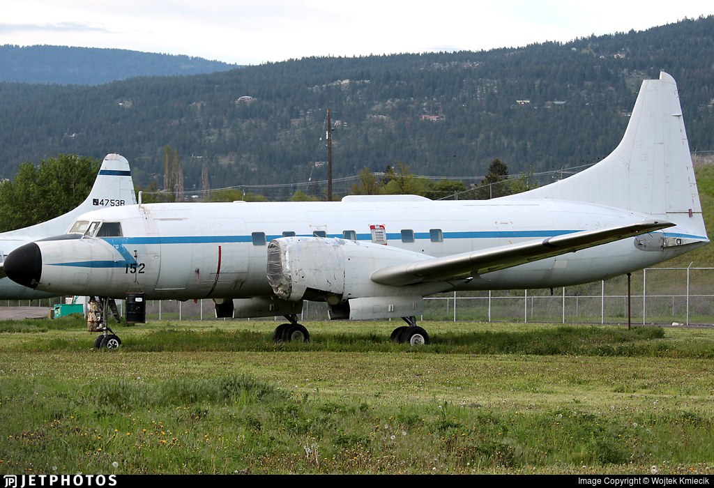 Canadair CC-109 Cosmopolitan 152 parked in grass with hills behind it.