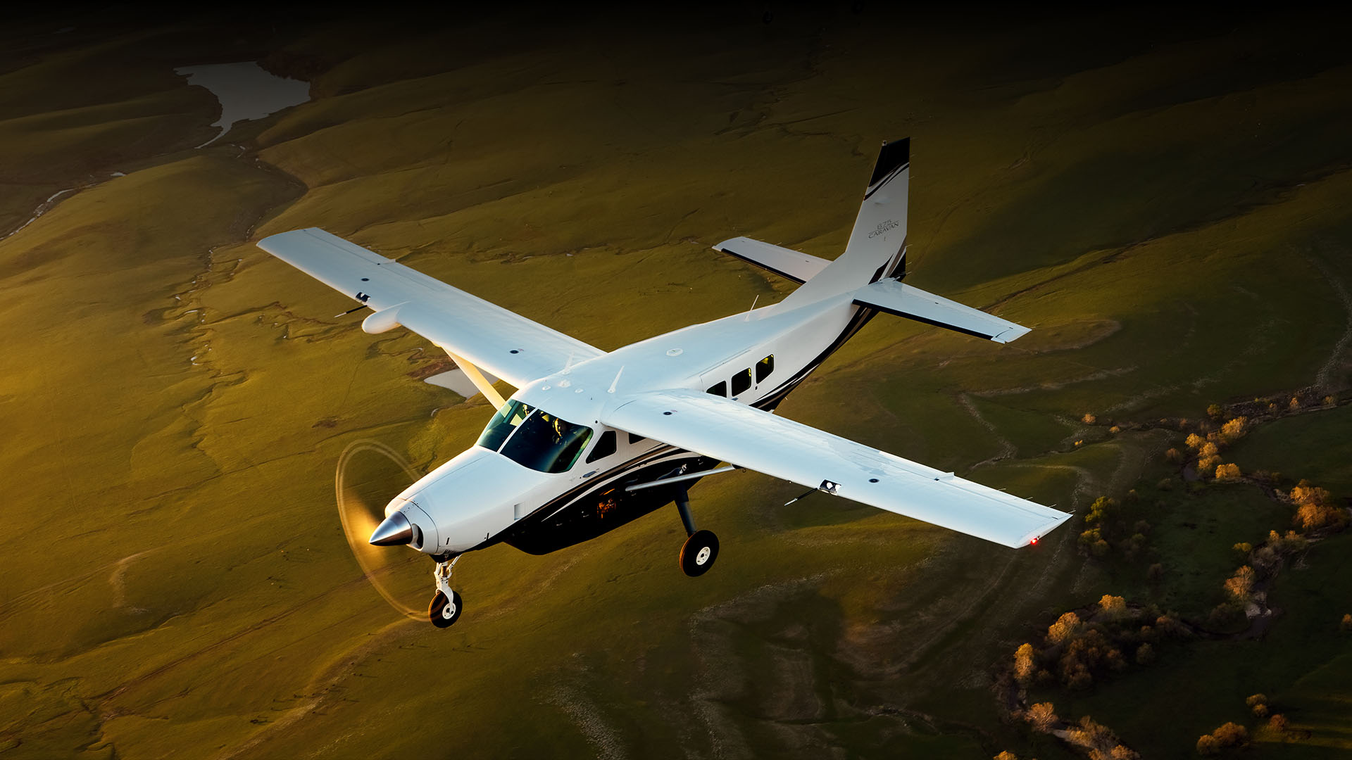 White Cessna Caravan single-engine turboprop flying over fields
