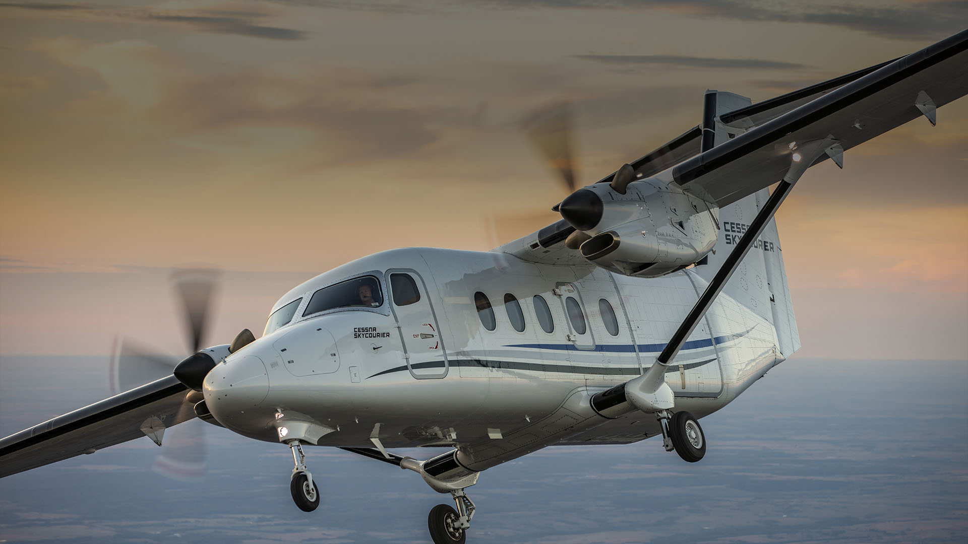 White Cessna SkyCourier twin turboprop flying with landing gear down