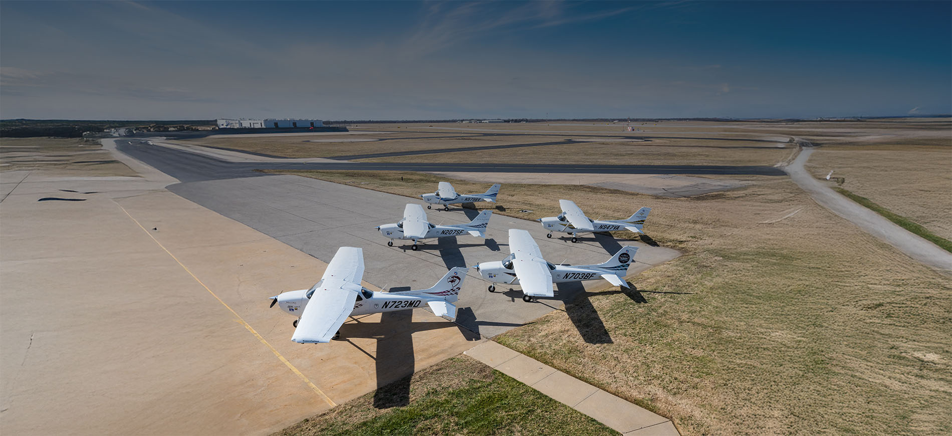 Several white Cessna high-wing piston aircraft parked near airport runways