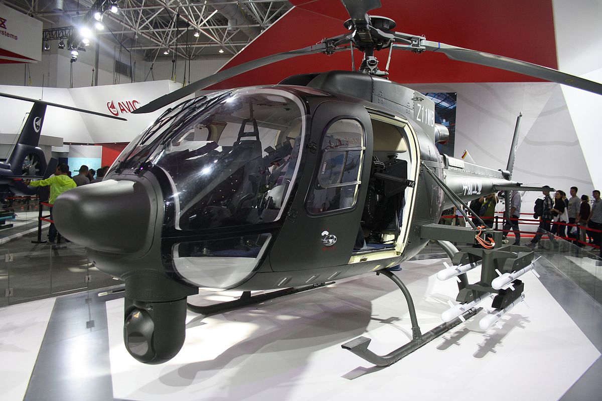Changhe Z-11WB displayed indoors with weapons arranged in front of the helicopter.