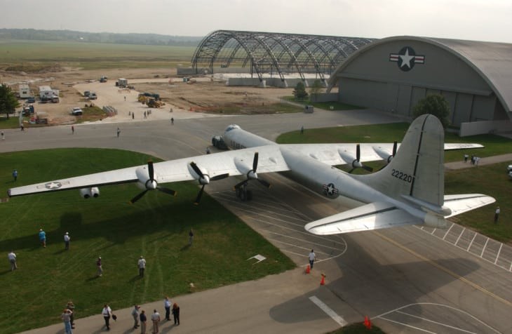 Convair B-36 Peacemaker outside arched hangars with people nearby.