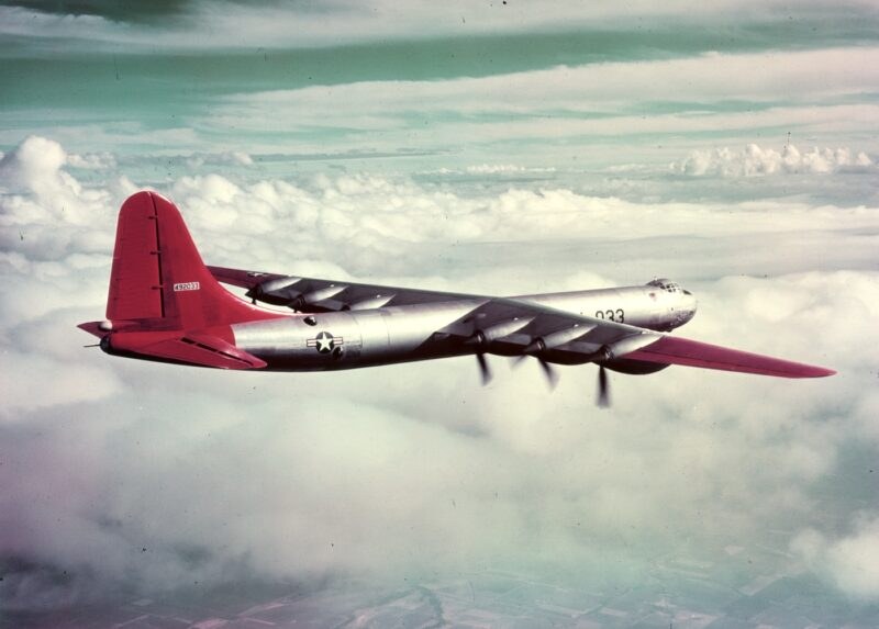 Convair B-36 Peacemaker with red tail and wing tips flying above clouds.