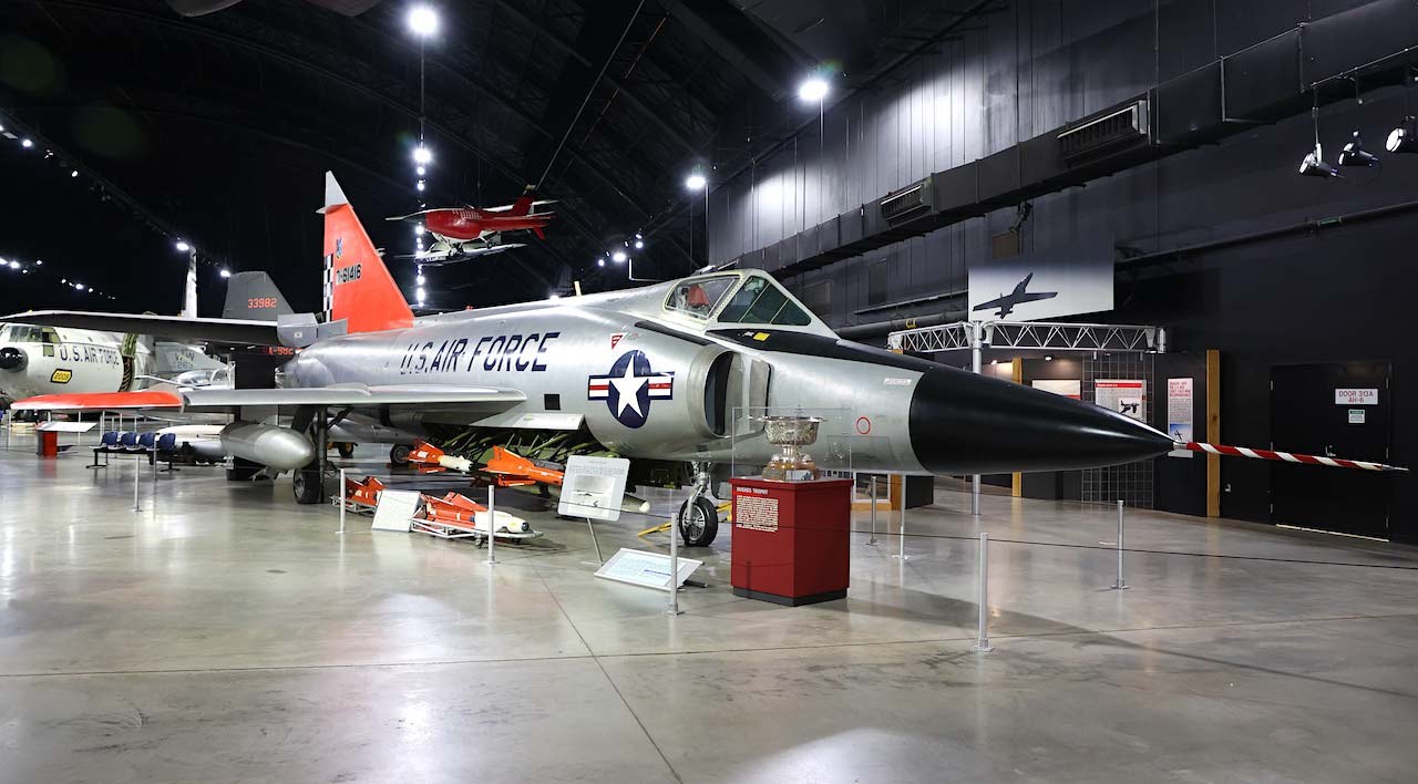 Convair F-102 Delta Dagger displayed indoors with missiles and exhibit barriers.