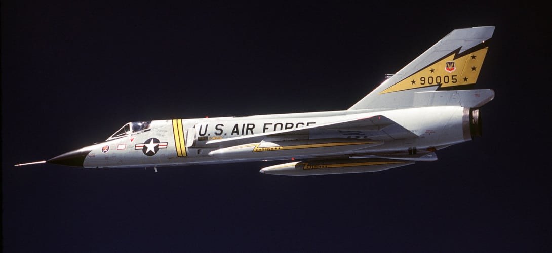 Convair F-106 Delta Dart 90005 flying in side profile against a dark background.