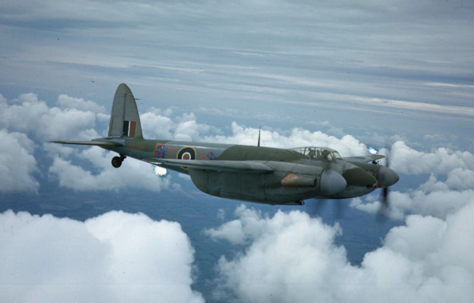 de Havilland Mosquito flying among clouds with RAF markings.